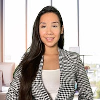 a woman in a houndstooth blazer standing in front of a desk